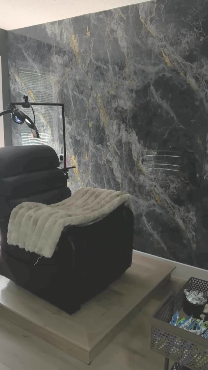The studio: a veined marble feature wall, a reclining lash chair with a faux-fur throw and a lamp